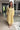 Woman wearing a yellow dress with floral patterns indoors.